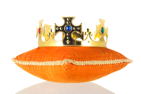 Orange royal velvet pillow with crown isolated over white backgroundの写真素材
