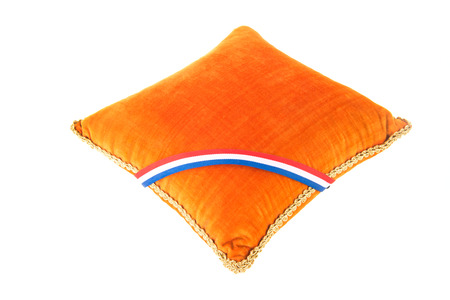 Velvet orange pillow with golden ribbon isolated over white backgroundの写真素材