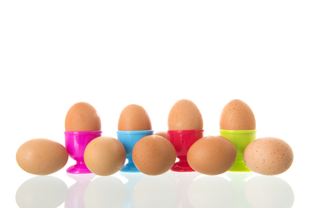Colorful egg cups with eggs isolated over white backgroundの写真素材