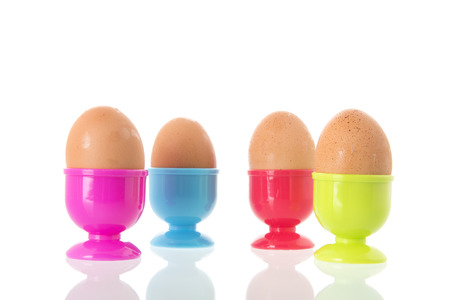 Colorful egg cups with eggs isolated over white backgroundの写真素材