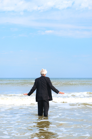 Business man in formal suit walking into the seaの写真素材