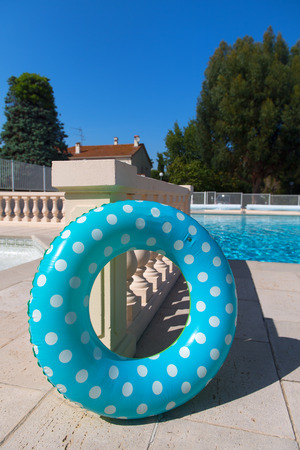 Floating ring toy in blue and green with swimming poolの写真素材