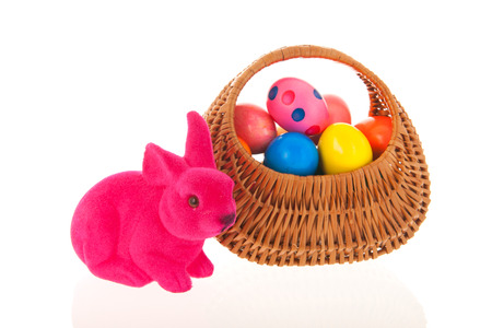 Wicker basket easter eggs and pink hare isolated over whiteの写真素材