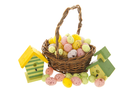 Easter eggs in basket with nest boxes for the birds isolated over whiteの写真素材