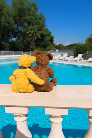 Two toy bears in love on wall at swimming poolの写真素材