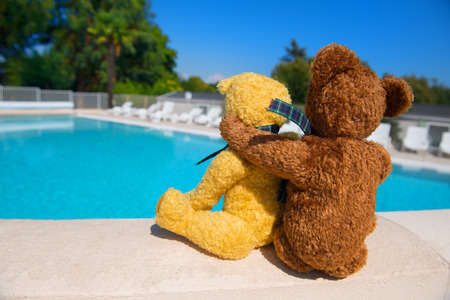 Two toy bears in love on wall at swimming poolの写真素材