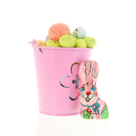 Full pastel colored easter eggs in bucket with chocolate hare isolated over whiteの写真素材