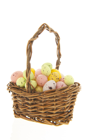 Easter eggs in wicker basket isolated over whiteの写真素材