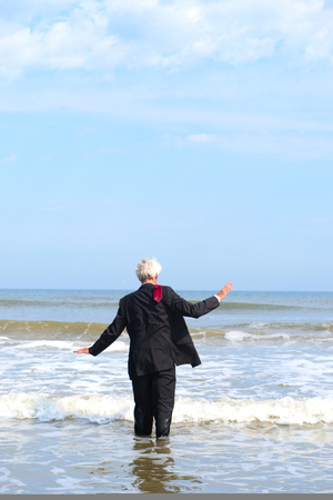 Business man in formal suit walking into the seaの写真素材