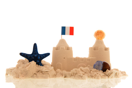 French sandcastle with red toys and flags isolated over whiteの写真素材