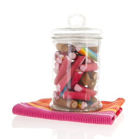 Glass pot of colorful candy canes isolated over whiteの写真素材