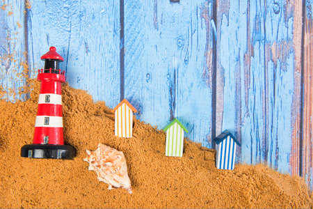 Lighthouse and beach huts in sand at the beachの写真素材