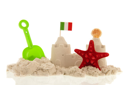 Italian sandcastle with red toys and flags isolated over whiteの写真素材