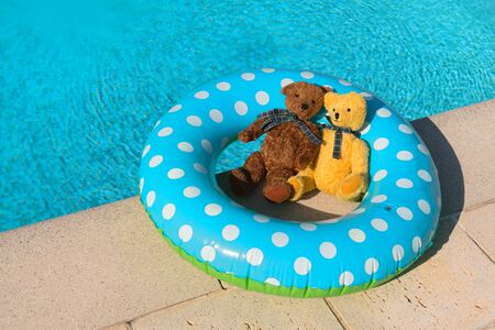 Two toy bears in inflatable toy in swimming poolの写真素材