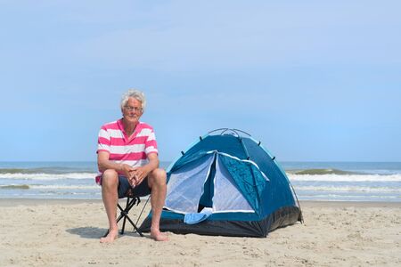 Single senior man camping in shelter at the beachの写真素材