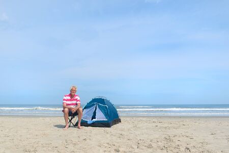 Single senior man camping in shelter at the beachの写真素材