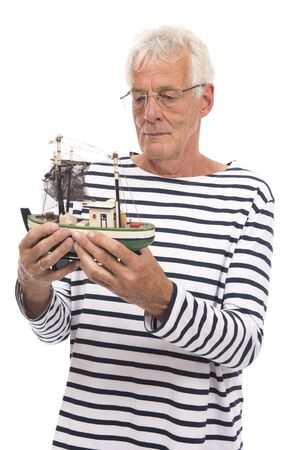 Old sailor holding wooden model fishing boatの写真素材