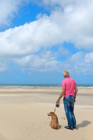Man standing with the dog at the beachの写真素材