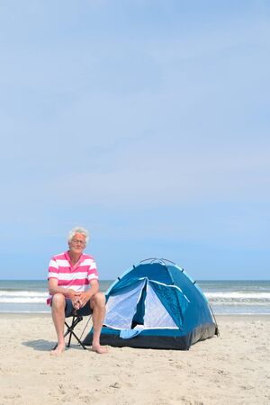 Single senior man camping in shelter at the beachの写真素材