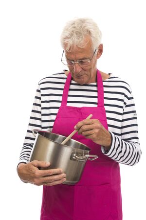Senior houseman with pink apron stirring in cooker pan isolated over whiteの写真素材