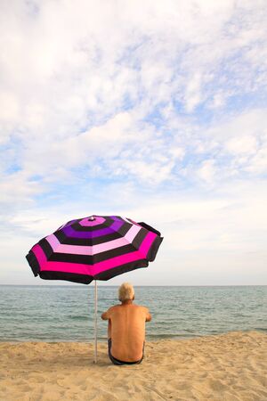 man on vacation with shade under umbrella at the beachの写真素材