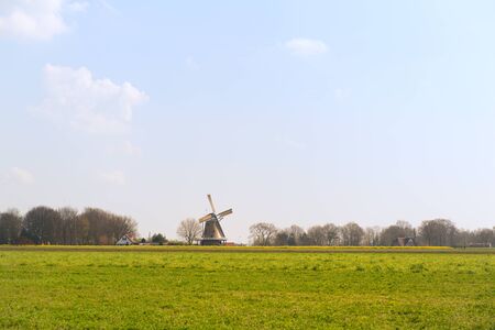 Classic windmill in Dutch village with rapeseedの写真素材