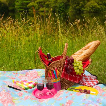 Wicker Picnic basket filled with bread grapes and wine outdoor in natureの写真素材