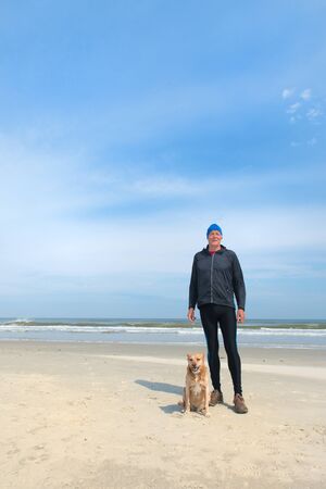 Healthy senior man as runner with his dog at the beachの写真素材