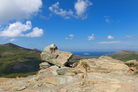 Landscape with rocks and French island Giraglia with lighthouse near Corseの写真素材