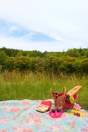 Wicker Picnic basket filled with bread grapes and wine outdoor in natureの写真素材