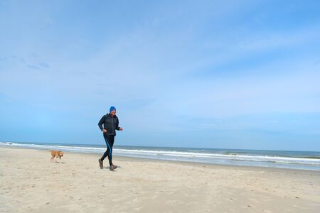Senior man with dog running together at the beachの写真素材