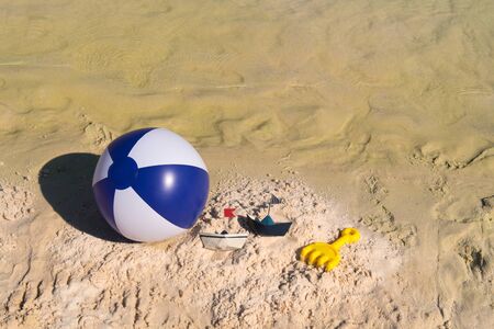 Several toys as ball and paper boat at the beachの写真素材