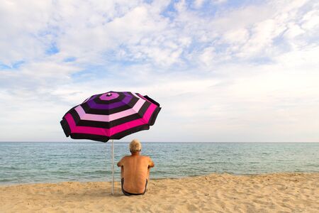 Man on vacation with shade under umbrella at the beachの写真素材