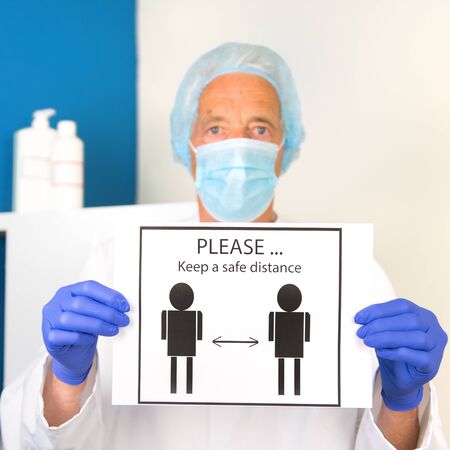 Doctor with face mask and protective clothing is asking for safe distanceの写真素材