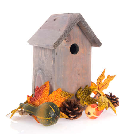 Birdhouse with autumn leaves isolated over white backgroundの写真素材