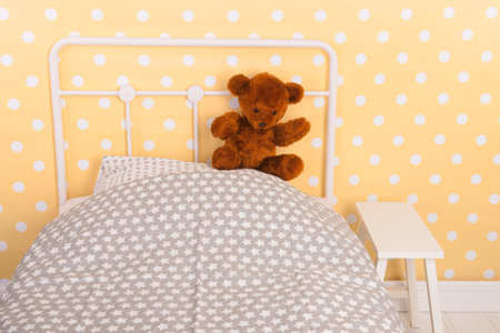 Bedroom with teddy bear sitting on bedの写真素材
