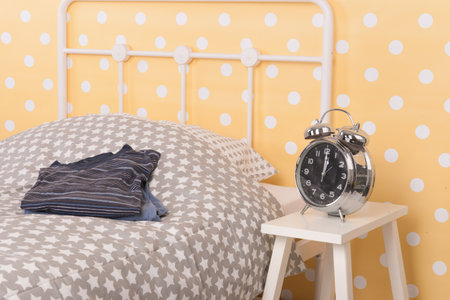 Yellow Bedroom with single bed, pajamas and alarm clockの写真素材
