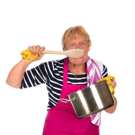 Elder woman tasting with pan and apron isolated over white backgroundの写真素材