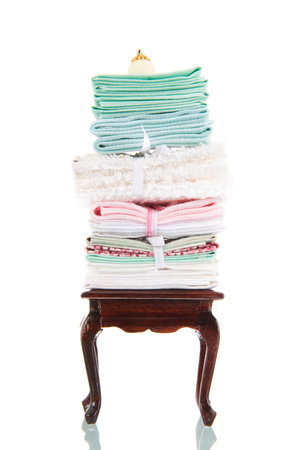 Queen ann style table with stack of antique linen isolated over white backgroundの写真素材