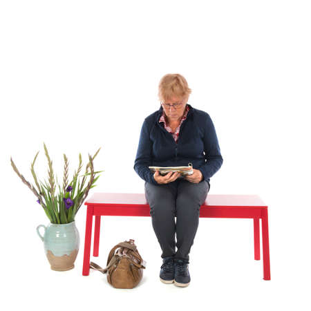 Senior woman is waiting and reading a magazineの写真素材