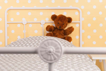 Bedroom with teddy bear sitting on bedの写真素材