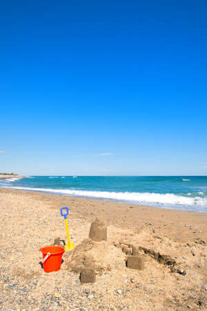 Colorful toy buckets and sand castle at the beachの写真素材