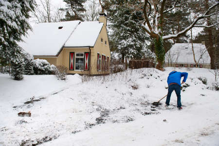 Man cleaning snow in typical Dutch landscapeの写真素材