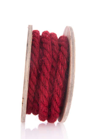 Simple red rope on wooden roll isolated over whiteの写真素材