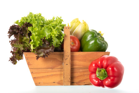 Wooden harvest basket with fresh vegetables isolated over whiteの写真素材