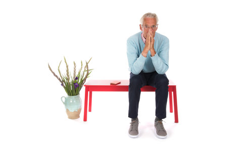 Senior man sitting in waiting room isolated over white backgroundの写真素材