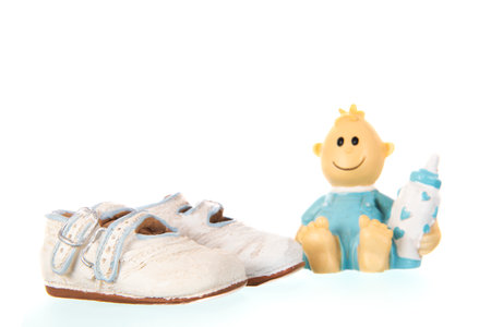 Artificial baby shoes and figurine isolated over white backgroundの写真素材
