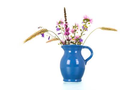 Bouquet wild flowers in blue vase isolated over white backgroundの写真素材