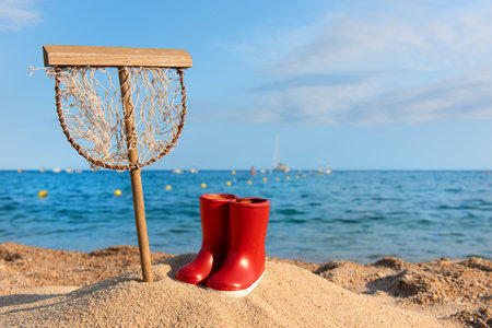 Landing net and boots at the beachの写真素材