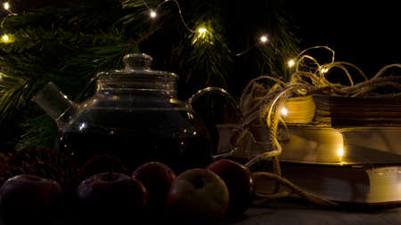 Glass teapot, old books, pine trees and apples. Garland lights. Night picture. Christmas mood.の写真素材